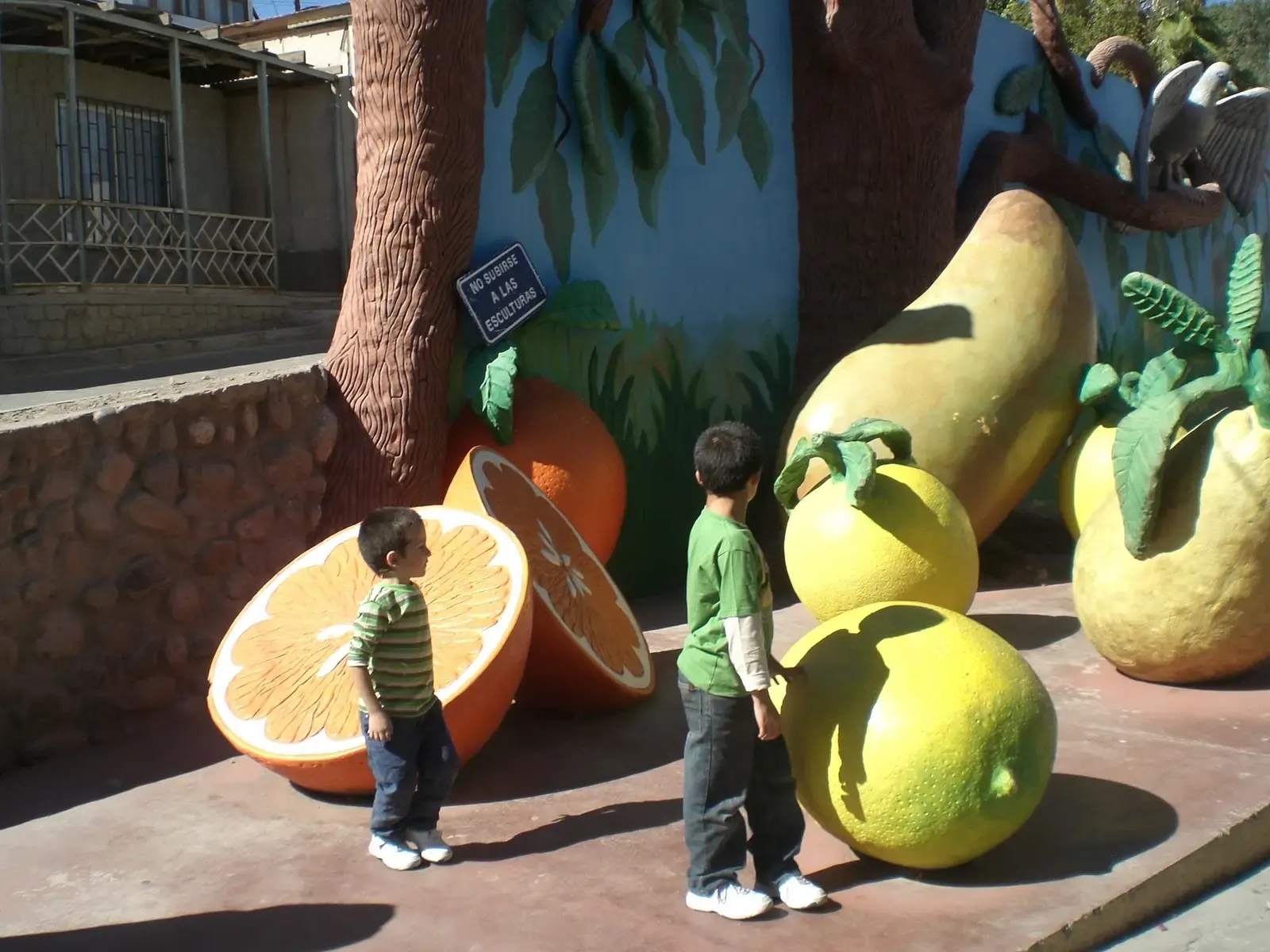 Dos niños miran esculturas gigantes de frutas