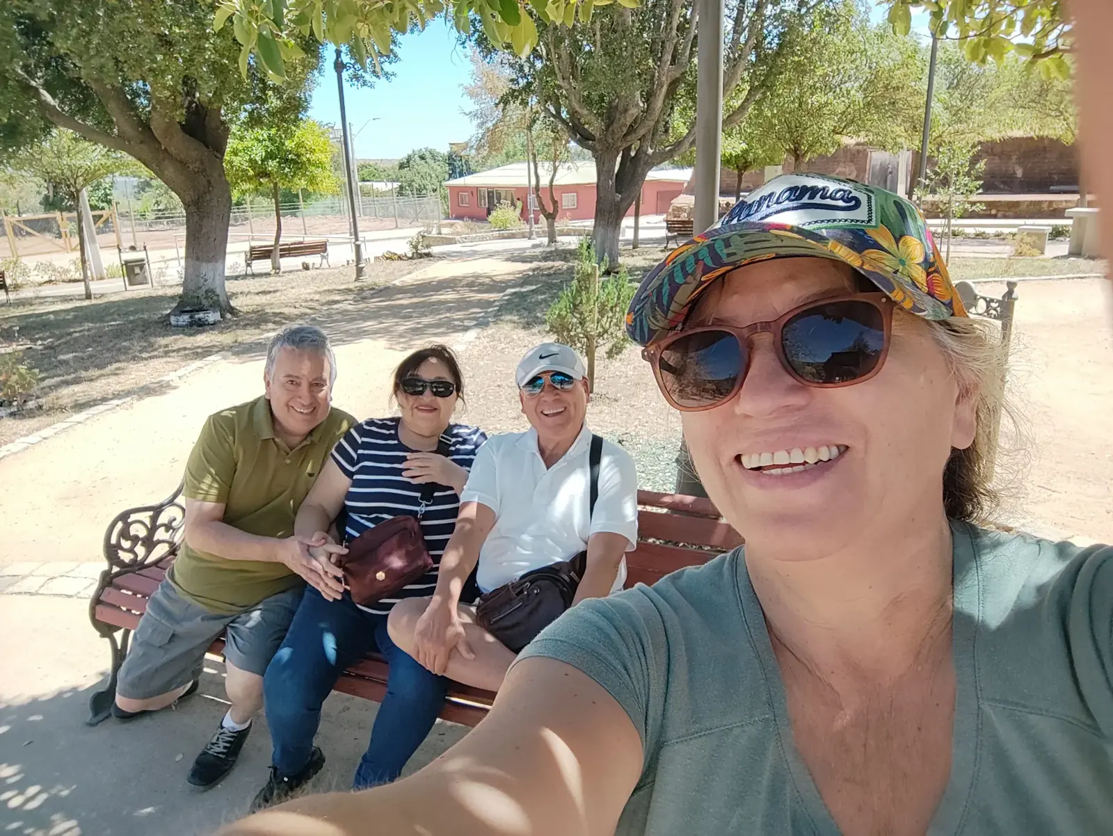 Una mujer se saca una selfie con tres amigos sentados en una banca